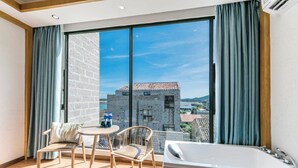 Ein Balkon mit Blick auf historische Gebäude, einer weißen Badewanne und zwei Stühlen.