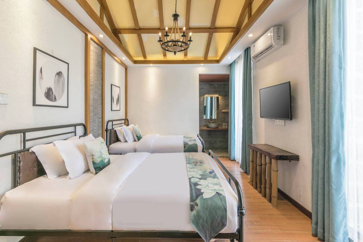A hotel room with a large bed, a TV, and a bathroom visible through an open door.