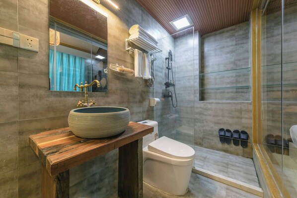 A modern bathroom with a large vessel sink, a toilet, a shower, and a glass-enclosed shower area. - gufengminsu (Fuzhou)