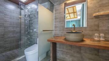 Un bagno moderno con doccia vetrata, un water bianco e un mobile bagno in legno con lavandino tondo.
