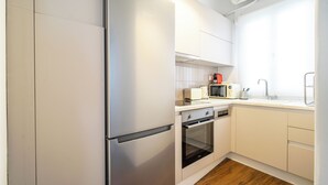 A modern kitchen with white cabinetry, a stainless steel refrigerator, a microwave, a toaster, and a sink. - Superb flat in historic centre of Athens (Athens)