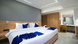 Una camera d'albergo moderna con un letto grande, una testiera in legno e una scrivania con una sedia.