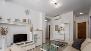 Un soggiorno moderno con una TV a schermo piatto, un tavolino in vetro e un divano color beige.