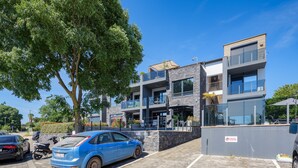 Un edificio moderno con un'area di parcheggio, un albero e un'auto blu.