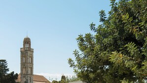 A poolside area with lounge chairs, a pergola, and a historic tower in the background.