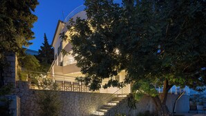 A modern building with a stone facade, a staircase leading to an upper level, and a well-maintained garden area.
