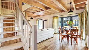 Een ruime slaapkamer met een groot bed, een houten trap en een zithoek met een tafel en stoelen.