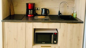 Een kleine keuken met een ingebouwde magnetron, koffiezetapparaat en een spoelbak.