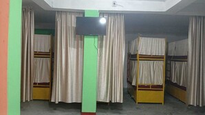 A dormitory room with bunk beds, curtains, and a television.
