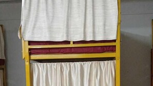 A bunk bed with a yellow frame and white bedding.