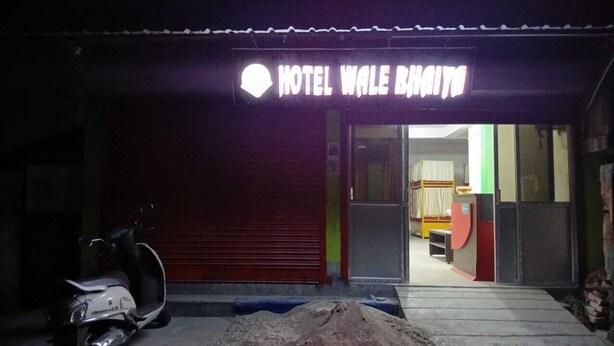 A hotel entrance with a closed shutter, a scooter parked outside, and a sign that reads "HOTEL WALE BHAIYA".