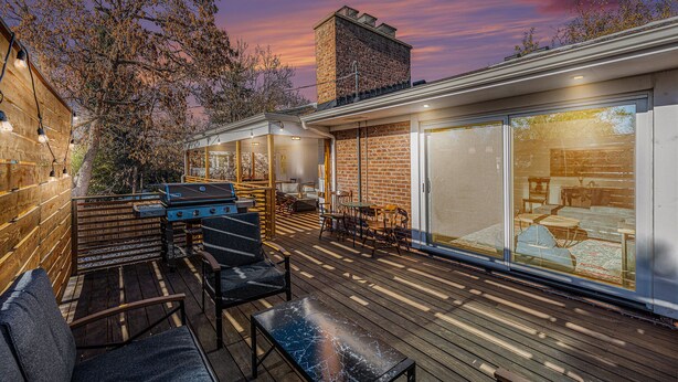 Une terrasse extérieure moderne, équipée d’un barbecue, de sièges et d’une porte vitrée donnant sur un espace de vie.