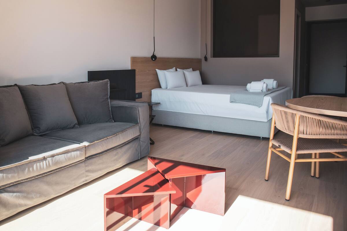 Een moderne hotelkamer met een bed, een bank, een kleine tafel en een stoel.