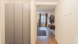 A hallway with a wardrobe, a TV, and a small table with a chair. - V Suite on Lake Como (Como)