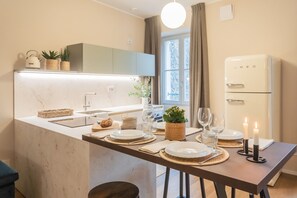 A modern kitchen with a marble countertop, a built-in oven, and a dining area set with plates, glasses, and candles. - V Suite on Lake Como (Como)