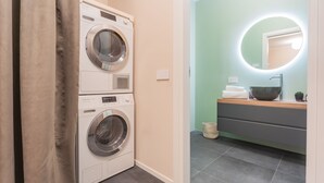 A laundry area with two washing machines, a sink with a mirror, and a wooden vanity. - V Suite on Lake Como (Como)