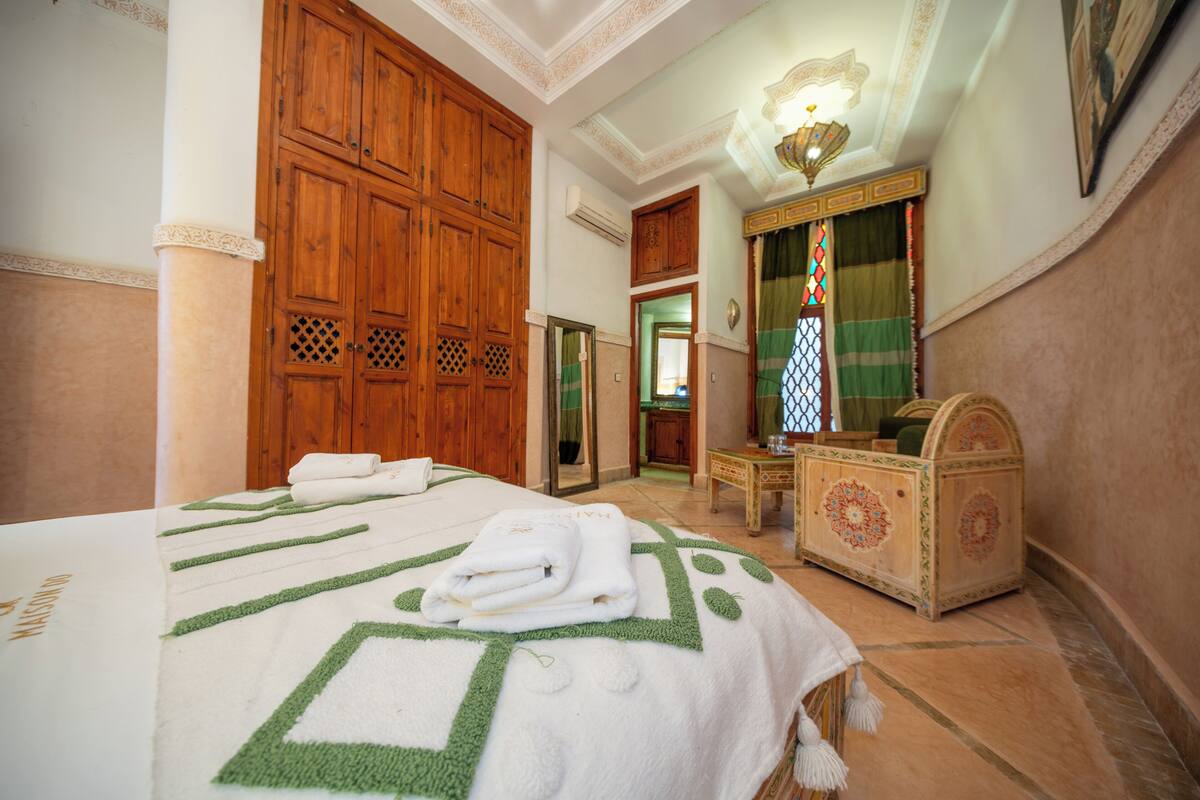Une chambre d’hôtel avec un grand lit, une armoire en bois et une petite table sur laquelle se trouve une boîte décorative.