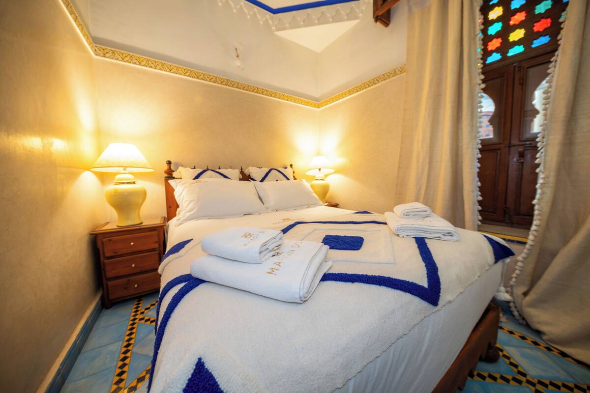 Une chambre d’hôtel avec un lit, deux tables de chevet et une petite table d’appoint.