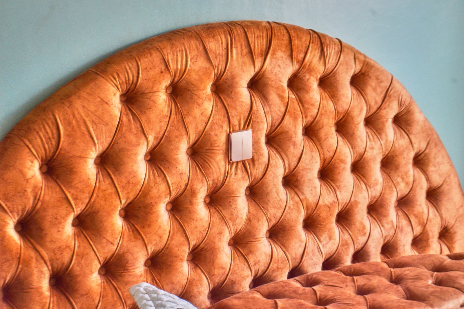 A tufted headboard with a button detail and a small white switch.