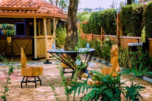An outdoor patio area with a wooden table and chairs, surrounded by plants and a brick floor. - Umugano Villa (Kigali)