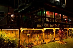 A traditional wooden structure with stone walls and hanging plants. - Umugano Villa (Kigali)
