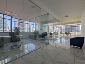 Work in style with a spacious office space featuring polished floors, glass partitions, and large windows offering a clear view of the city.