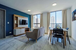 Relax in this stylish living room with a large flat-screen TV, comfortable sofa, and dining area.