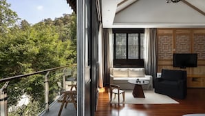 A modern room with a balcony, a sofa, a TV, and a dining table. - GRAND JOLI (Lijiang)