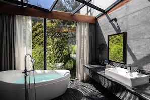 A modern bathroom with a freestanding bathtub, a sink, and a large mirror.