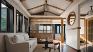 A modern interior with a white sofa, a round table, and a wooden partition. - GRAND JOLI (Lijiang)