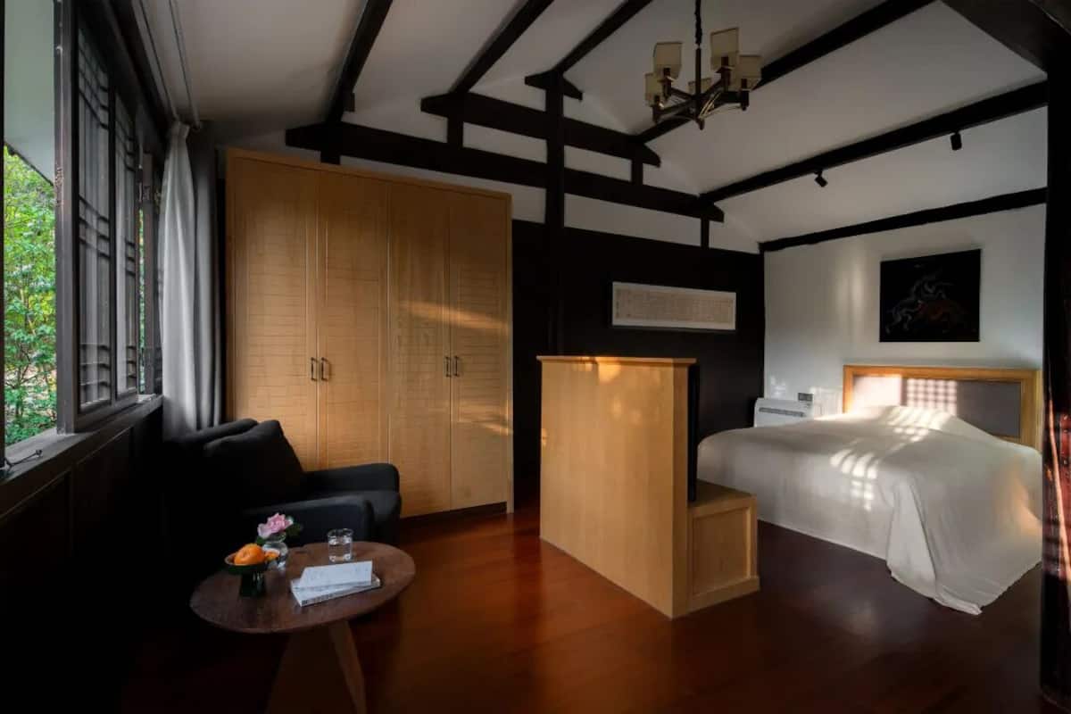 Ein Schlafzimmer mit einem Bett, einem Holzschrank, einem kleinen Schreibtisch und einem Fenster mit Vorhängen.