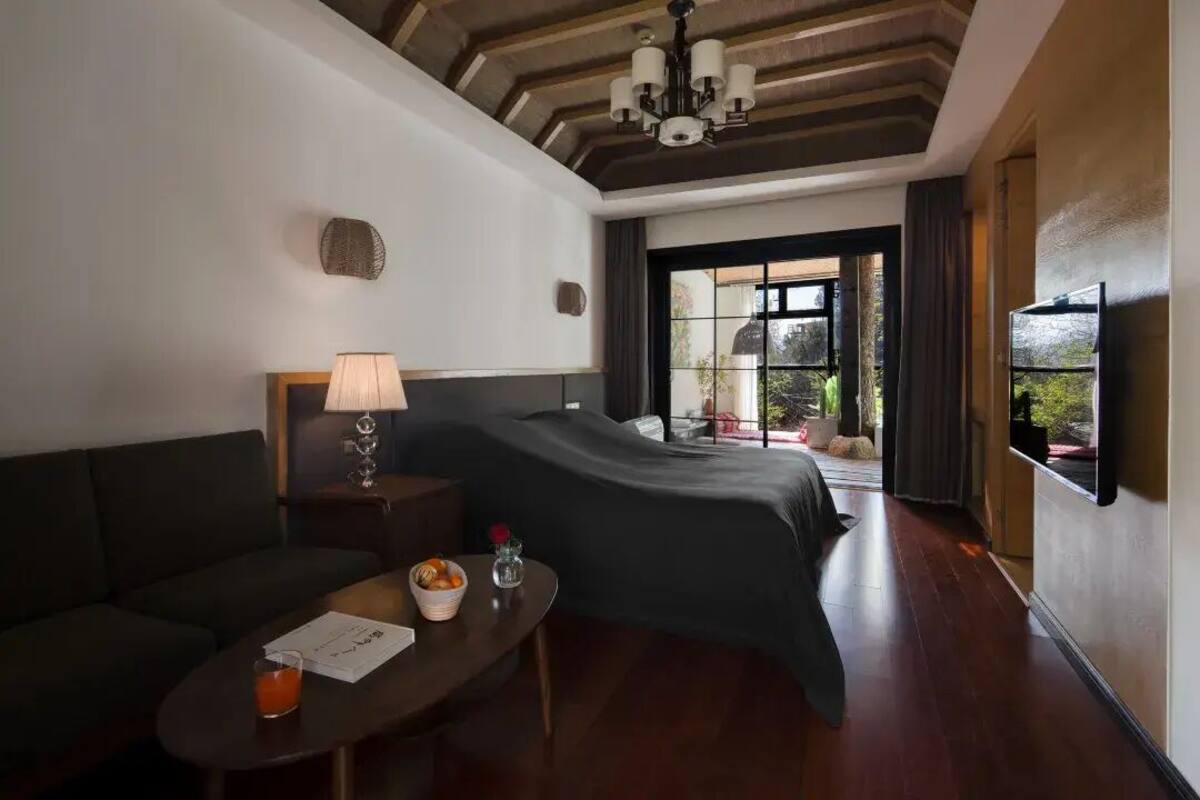 Ein Hotelzimmer mit Bett, Sofa, Tisch mit Lampe und Fernseher.