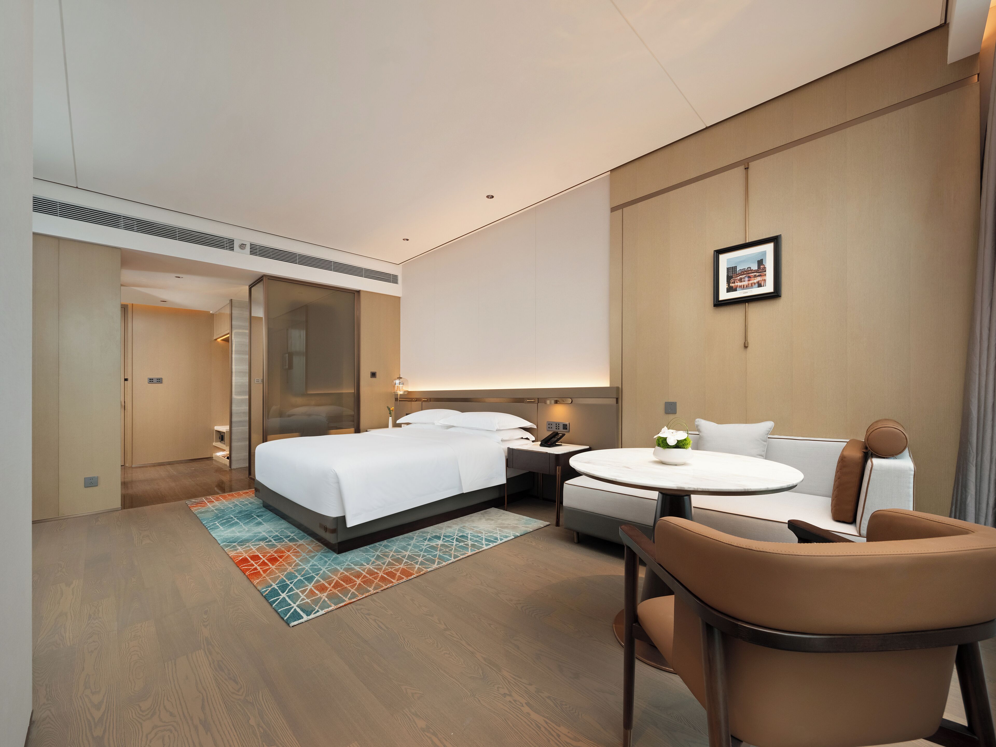 Una habitación de hotel moderna con una cama grande, un escritorio, una silla y una pequeña mesa redonda.