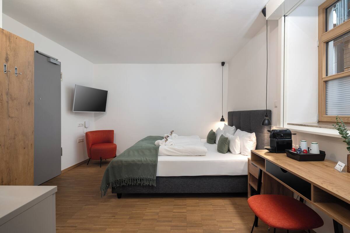 Une chambre à coucher moderne, équipée d’un lit, d’un bureau, d’une chaise, d’une télévision et d’une fenêtre.