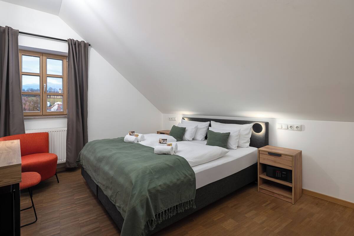 Une chambre à coucher moderne avec un lit, une table de chevet et un bureau avec une chaise.