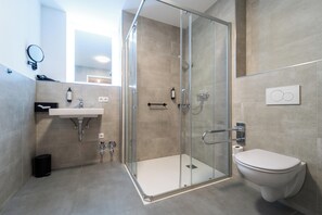 A modern bathroom with a glass shower enclosure, a white sink, and a toilet. - dreamcation Altstadthotel Regensburg (Regensburg)