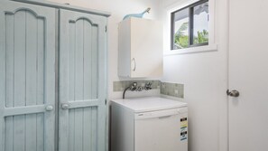 Een badkamer met een wit wastafelmeubel, een spiegel en een raam met uitzicht op palmbomen.