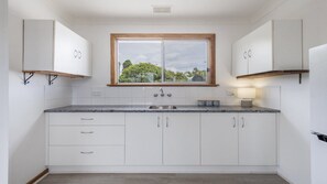 A modern kitchen with white cabinets, a granite countertop, a double sink, and a window with a view of greenery.