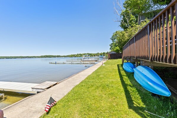 A lakeside dock with boats, a grassy area, and a wooden fence.