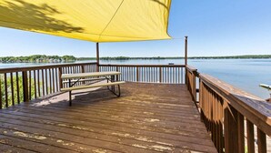 Une terrasse en bois avec une table de pique-nique et un auvent jaune.