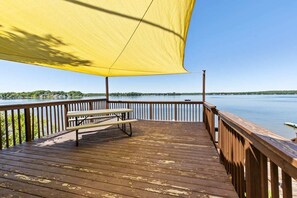 Eine Holzterrasse mit Picknicktisch und einem gelben Sonnensegel.