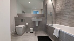 A modern bathroom with a toilet, sink, and bathtub.