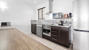 A modern kitchen with stainless steel appliances, a dishwasher, and a built-in oven. - Mango Resort 1 Bedroom 45A Palm Cove (Palm Cove)