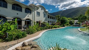 A resort with a swimming pool, lush greenery, and a mountain backdrop. - Mango Resort Studio 45B (Palm Cove)