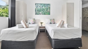 A hotel room with two beds, a small table with a plant, and a large forest-themed painting on the wall. - Mango Resort Studio 45B (Palm Cove)