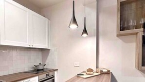 A modern kitchen with white cabinets, a wooden countertop, a built-in oven, and two hanging pendant lights. - Par71 - Marco Simone golf club Roma (Marco Simone)