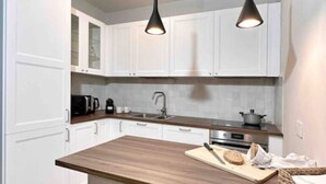 A modern kitchen with white cabinets, a wooden countertop, and two pendant lights. - Par71 - Marco Simone golf club Roma (Marco Simone)