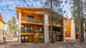Une cabane en bois à plusieurs étages, dotée de balcons et entourée d’arbres.