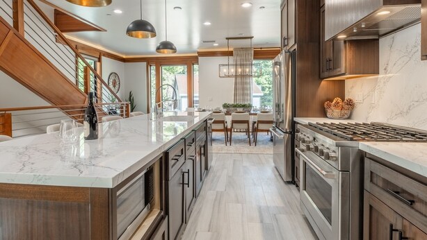 Une cuisine moderne dotée d’un îlot central, d’appareils électroménagers en acier inoxydable et de meubles de rangement en bois.