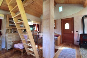A wooden interior with a wooden staircase, a door with a window, and a fireplace.